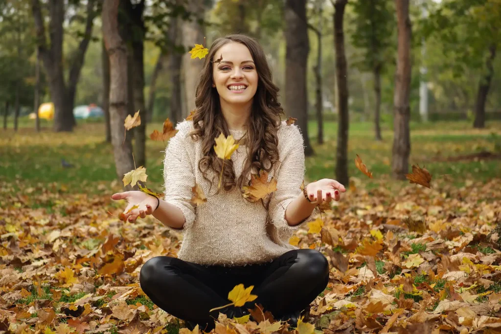 Girl Smiling Sitting In Maple Leaves